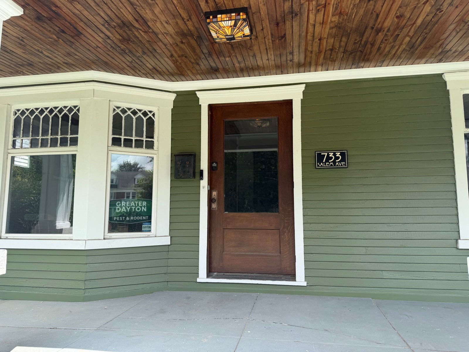 The restored front porch of the Greater Dayton Pest & Rodent office at 733 Salem Ave in Dayton’s Historic Five Oaks neighborhood — original oak door, leaded-glass windows, and stained beadboard ceiling